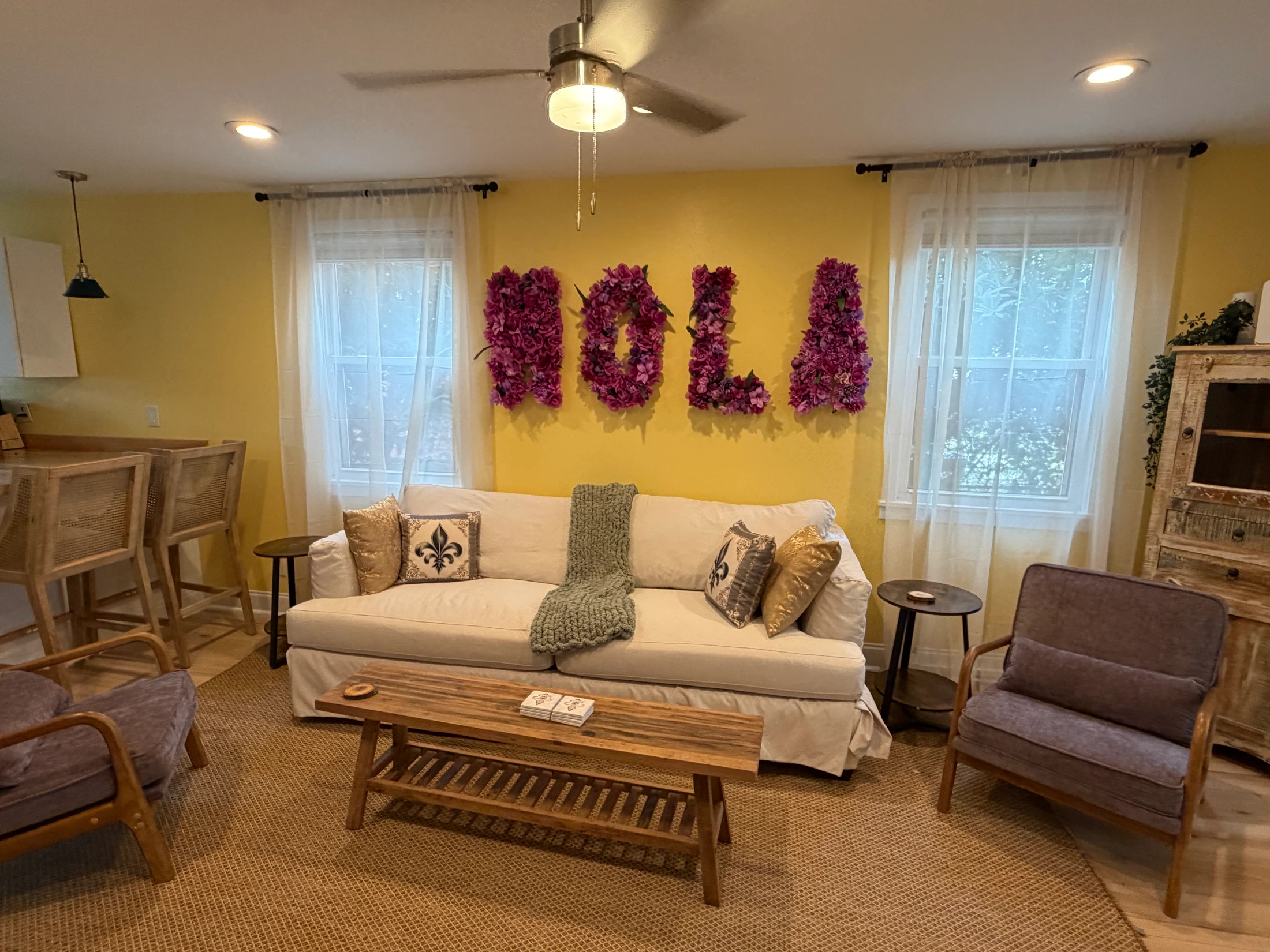 1616 Independence living room with a white sofa and purple floral NOLA letters on a yellow wall